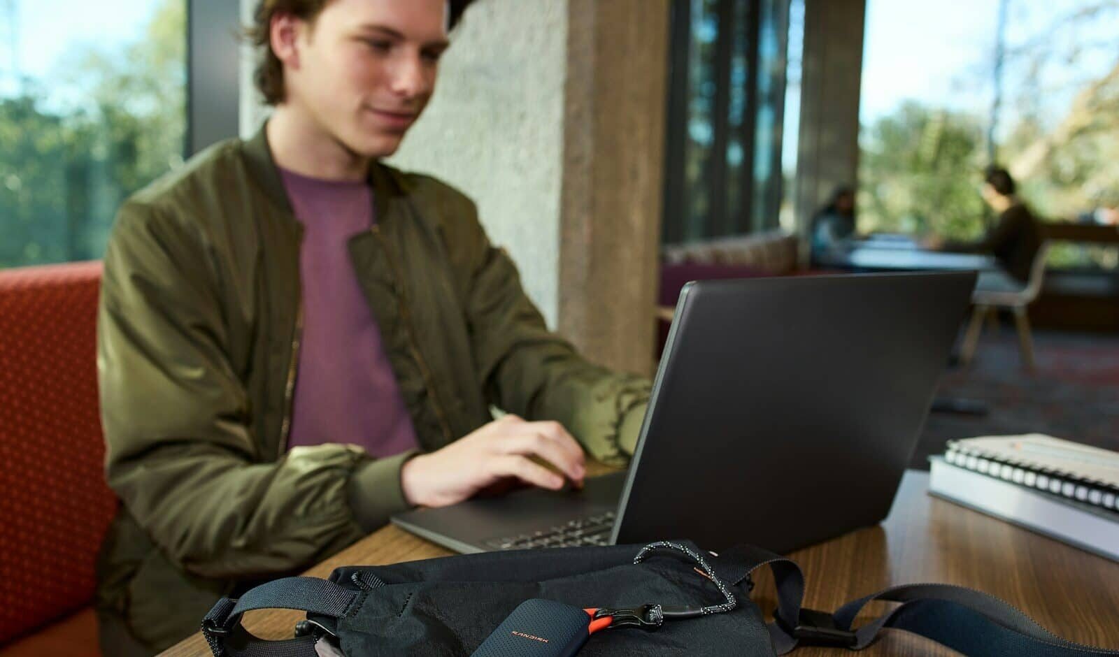Young man uses laptop, portable storage device on table